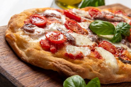 Foto de Deliciosa pizza típica romana con tomate, mozzarella y anchoas, comida italiana - Imagen libre de derechos
