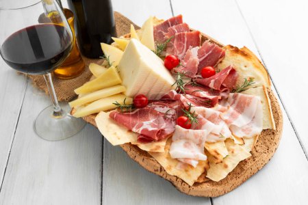 Foto de Bandeja de delicioso pecorino, guanciale, jamón y una copa de vino tinto, gastronomía sarda, comida italiana - Imagen libre de derechos