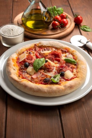 Foto de Deliciosa pizza italiana con mozzarella, salsa de tomate, aceitunas negras, copos de grana y jamón, comida europea - Imagen libre de derechos