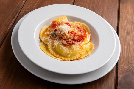 Téléchargez les photos : Assiette de délicieux raviolis garnie de sauce tomate et parmesan et farcie de ricotta, pâtes italiennes, nourriture européenne - en image libre de droit