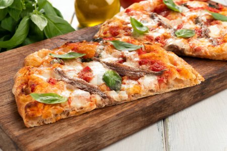 Foto de Deliciosa pinsa en rodajas, una pizza de estilo romano con salsa de tomate, mozzarella y anchoas, comida italiana - Imagen libre de derechos