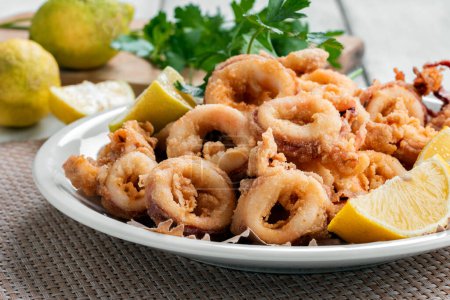 Photo for Plate of delicious fried calamari rings with sliced lemon, Italian cuisine, Mediterranean food - Royalty Free Image