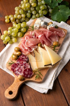 Photo for Closeup of delicious cheeses, salami and fresh fruit, Italian gastronomy, European food - Royalty Free Image