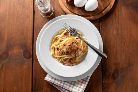 Photo for Closeup of delicious bucatini alla carbonara, a traditional roman recipe of pasta with guanciale, egg sauce, roman pecorino and black pepper, Italian food - Royalty Free Image