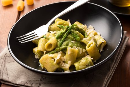 Photo for Close-up shot of delicious pasta with asparagus on wooden tabletop - Royalty Free Image