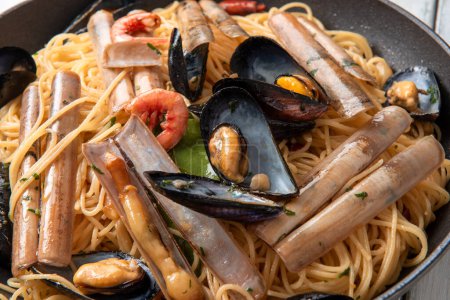 Téléchargez les photos : Gros plan de délicieuses pâtes aux fruits de mer sur une table en bois blanc - en image libre de droit