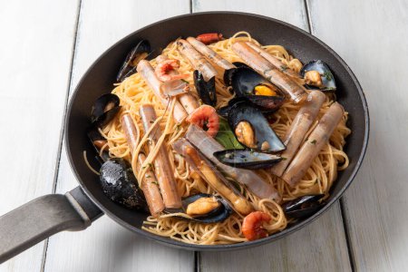 Téléchargez les photos : Gros plan de délicieuses pâtes aux fruits de mer sur une table en bois blanc - en image libre de droit