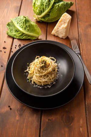 Foto de Placa de deliciosos espaguetis con salsa de cacio, pimienta negra y col savoy, pasta italiana vegetariana, comida europea - Imagen libre de derechos