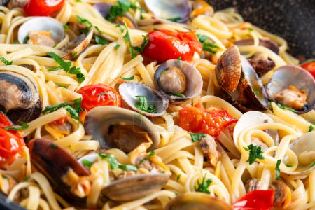 Großaufnahme köstlicher Linguine mit Venusmuscheln, Tomaten und Petersilie, italienische Pasta, europäisches Essen
