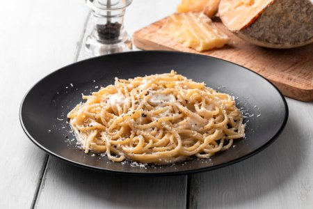 Plate of delicious typical spaghetti cacio and pepe, a roman recipe of pasta with black pepper and cheese sauce, italian food
