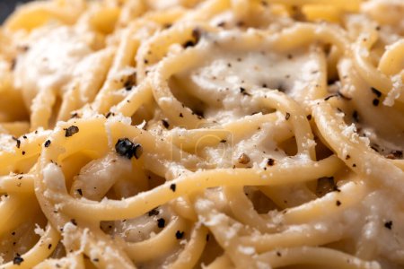 Foto de Placa de deliciosos espaguetis típicos cacio y pepe, una receta romana de pasta con salsa de pimienta negra y queso, comida italiana - Imagen libre de derechos
