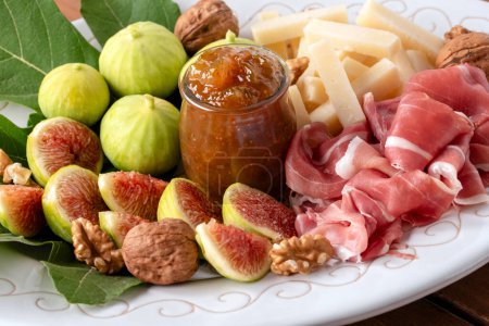 Photo for Closeup of fresh figs, fruit jam, pecorino, walnuts and sliced prosciutto crudo, italian appetizers, european food - Royalty Free Image