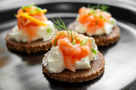 Photo for Closeup of delicious canapes topped with cheese cream and smoked salmon, fresh european appetizers - Royalty Free Image