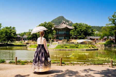 Photo for Seoul, South Korea. Hanbok wearing woman. Gyeongbokgung palace park garden. Korean dress tradition. Hyangwonjeong Pavilion in the background. Tourist in Gyeongbok. Traditional culture tour and travel. - Royalty Free Image