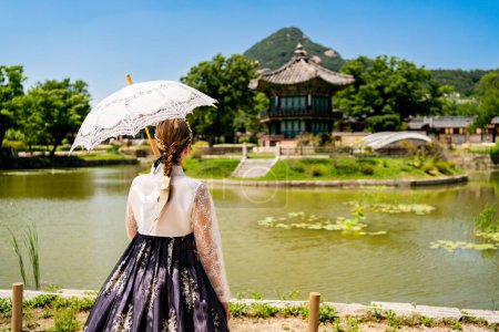 South Korea, Seoul. Woman in hanbok. Gyeongbokgung palace park garden. Hyangwonjeong Pavilion in the background. Korean dress tradition. Tourist in Gyeongbok. Traditional culture tour and travel.