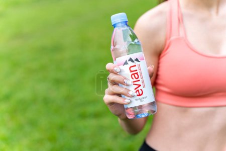 Foto de Editorial ilustrativo de la famosa botella de agua francesa Evian en mano femenina. Evian es una marca francesa de agua de primera calidad. POLTAVA, UCRANIA - 08 de junio de 2023. - Imagen libre de derechos