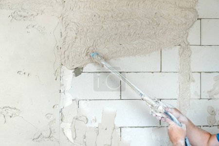 Photo for Machine plastering. Applying gypsum plaster by mechanized method on the surface of foam blocks. - Royalty Free Image
