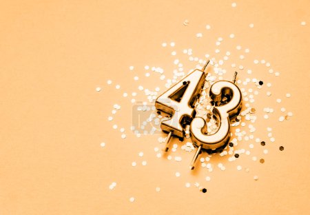Téléchargez les photos : 43 ans anniversaire célébration fond festif fait avec une bougie d'or sous la forme de nombre Quarante-trois couché sur des étincelles. - en image libre de droit