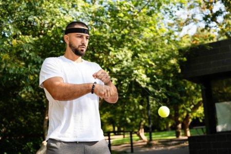 Boxer fighter trains with a boxing fight ball in the park for improved reflexes and coordination