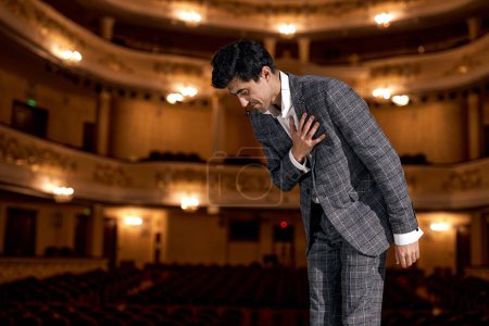 Foto de Man Presenter in elegant classic suit on Stage is expressing gratitude to audience after performance, bow down, handsome american or european guy after successful presentation, skilled and talented - Imagen libre de derechos