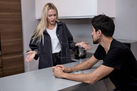 Téléchargez les photos : Young Caucasian Couple Have Disagreement in Kitchen at Home. Quarrel in Young Family. Angry Wife. Divorce Concept. Upset Husband. Relationship between People Concept. Conversation in Kitchen. - en image libre de droit