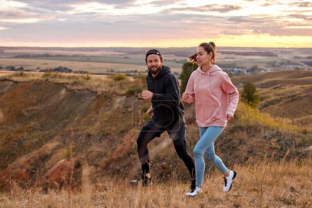 Foto de Couple running at sunset or sunrise along field mountains, morning jogging of healthy lifestyle at dawn, cardio load increasing heart rate, time to dream, fitness training generation z - Imagen libre de derechos