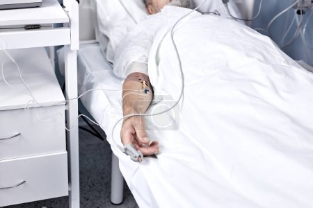 Téléchargez les photos : Ill senior male patient in hospital bed. Healthcare and treatments concept. mature man recovering after Covid 19, coronavirus. man is injected, lies with a dropper in modern hospital. close-up hands - en image libre de droit