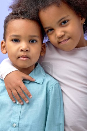 Photo for Close-up portrait of nice black kids hugging posing looking at camera, isolated on purple studio background. adorable children with dark skin brother and sister, friendly family concept - Royalty Free Image