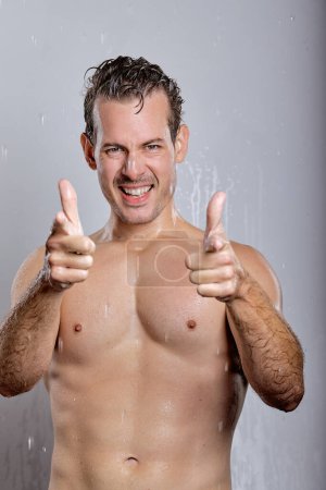Téléchargez les photos : Happy shirtless young man with perfect skin showing at you, look at camera, having sexy muscular body, isolated on gray studio background, portrait. Skin care healthcare cosmetic procedures concept - en image libre de droit