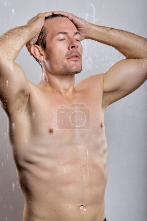Photo for Relaxed Handsome macho man guy holding hands touch perfect hairdo topless, get shower. sporty torso metrosexual hot tender body isolated over grey background. Portrait of naked muscular model - Royalty Free Image