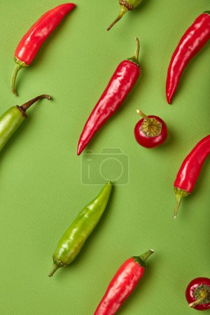 Foto de Many ripe fruits of red chilli peppers isolated on green background, flat lay, top view - Imagen libre de derechos