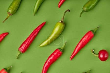 Foto de Many ripe fruits of red chilli peppers isolated on green background, flat lay, top view - Imagen libre de derechos