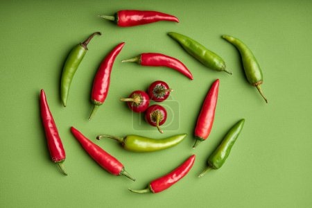 Foto de Spicy red hot chilli pepper on green background. Copy space for text. Top view or flat lay. Group of red peppers isolated on green background - Imagen libre de derechos