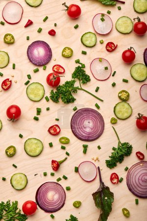 Foto de Slices of cucumber, onion, greenery, tomato cherry popular spices concept. top view on fresh beautiful vegetables scattered on soft yellow background, top view, flat lay - Imagen libre de derechos
