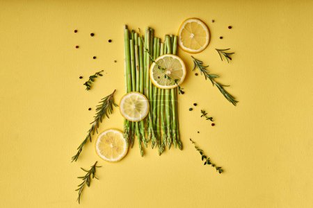 Foto de Creative shot of Asparagus. fresh green asparagus close-up with slice of lemon isolated on yellow background. Healthy vegetarian food. flat lay, copy space - Imagen libre de derechos