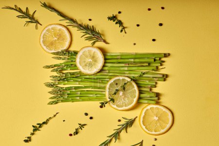 Téléchargez les photos : Top view on Asparagus. fresh green asparagus close-up with slice of lemon isolated on yellow background. Healthy vegetarian food. flat lay, copy space - en image libre de droit