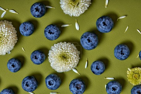 Téléchargez les photos : Creative layout made of fresh blueberry and flowers on green background. Flat lay. Food concept. Macro concept. Copy space for ad. vitamin fruit - en image libre de droit