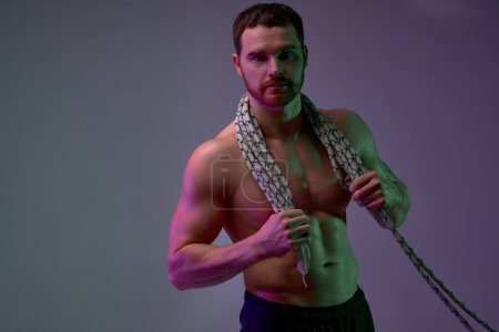 Photo for Handsome muscular man with rope on neck looking at the camera. copy space. isolated blue background. strength training. beauty - Royalty Free Image