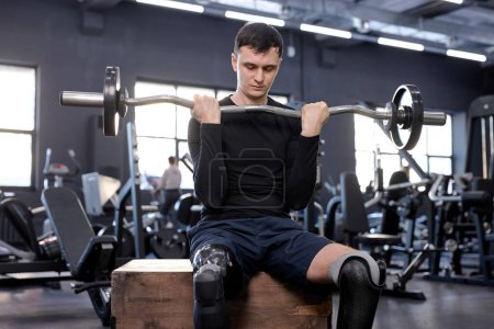 Photo for Ambitious awesome man performs barbell exercises, sitting on wooden box. lower body and core strength training exercises. cross fit - Royalty Free Image