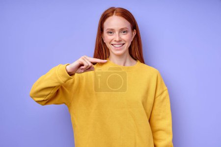 Téléchargez les photos : Femme blanche gaie avec de longs cheveux rouges démontrant la lettre H. symbole de langue des signes pour sourd humain en fond bleu. isolé - en image libre de droit