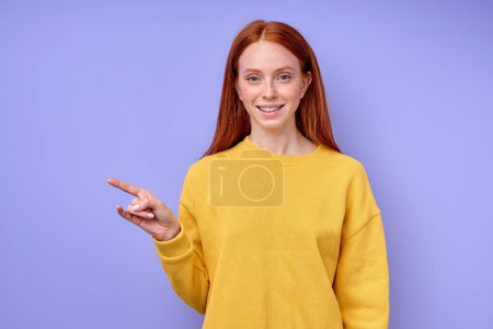 Photo for Beautiful happy confident redhead woman in yellow stylish sweater demonstrating letter Z sign language symbol for deaf human with blue background. isolated close up portrait - Royalty Free Image