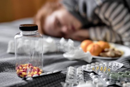 Photo for Close up shot. focus on bottle of vitamins, pills medicine, unhealthy ginger woman sleeping in the blurred background - Royalty Free Image