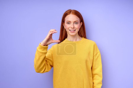 Foto de Joven sonriente mujer sorda pelirroja usando suéter amarillo usando lenguaje de señas sobre fondo azul, niña enseñando a los niños sordos al alfabeto, educación de cerca retrato, mujer muestra letra C - Imagen libre de derechos