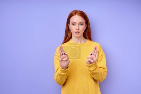 Foto de Joven pelirroja sorda muda mujer usando lenguaje de señas, explicando sobre fondo azul, primer plano retrato - Imagen libre de derechos