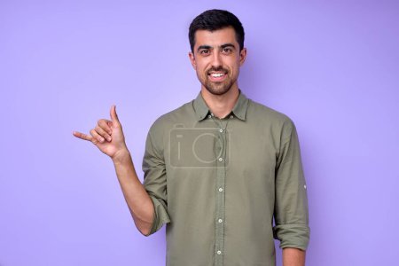 Photo for Cheerful brunette bearded man demonstrating the letter Y y . sign language symbol for deaf human in blue background. isolated - Royalty Free Image