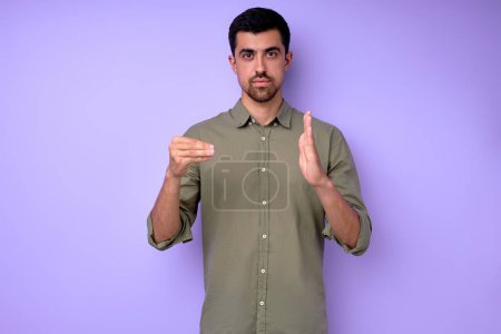 Téléchargez les photos : Jeune homme sourd-muet barbu grave montrant le numéro 500 en utilisant le langage des signes sur fond bleu isolé portrait rapproché - en image libre de droit