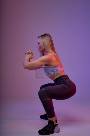 Téléchargez les photos : Profil de la femme sportive faisant squats, pleine longueur vue latérale photo. coordination, motivation, temps libre, temps libre, mode de vie - en image libre de droit