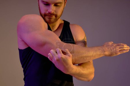 Photo for Strong bearded man boasts with his biceps, looking at his arm,focus on muscular arm , close up cropped photo. isolated brown background. motivation, man has problems with his arm, hurt arm, injury - Royalty Free Image