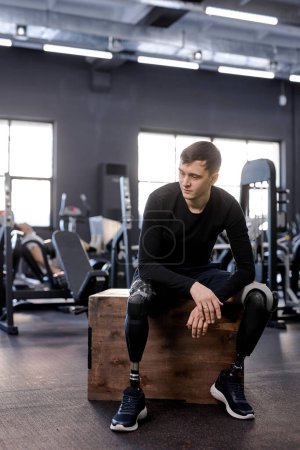 Photo for Young handsome brunette man in black sportswear has rest after hard workout, full length photo. rest. guy takes break - Royalty Free Image