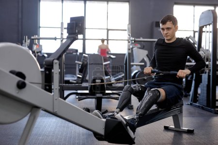 Photo for Strong man concentrated on pilling rowing machine, side view shot. total-body fitness - Royalty Free Image